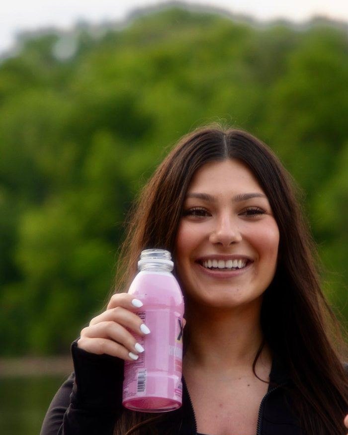 Smiling with a bottle of X Hydration Strawberry Lemonade
